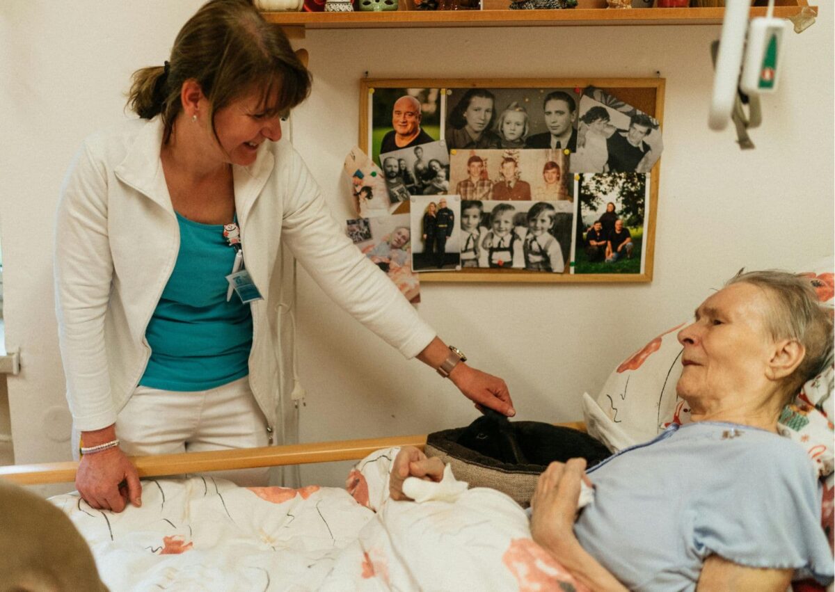Soignante tenant la main d'un patient en soins palliatifs