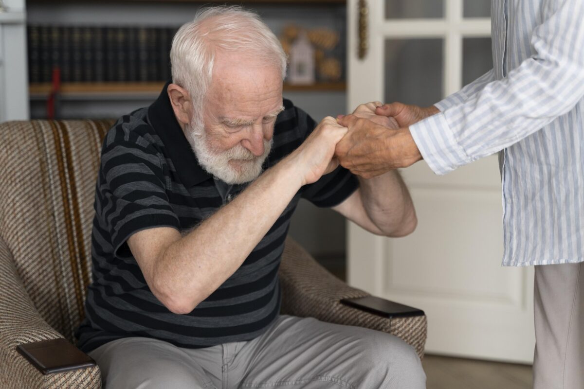 Main d'une personne âgée atteinte de la maladie de Parkinson, tenue par un proche